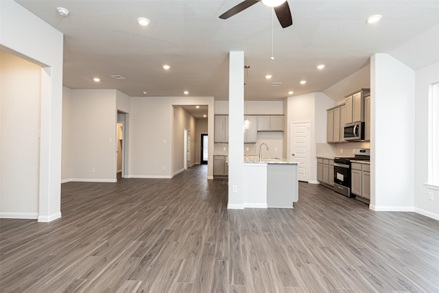 kitchen with stainless steel appliances, recessed lighting, gray cabinets, open floor plan, and wood finished floors