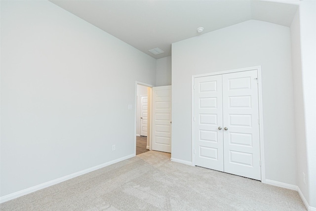 unfurnished bedroom with visible vents, baseboards, lofted ceiling, carpet, and a closet