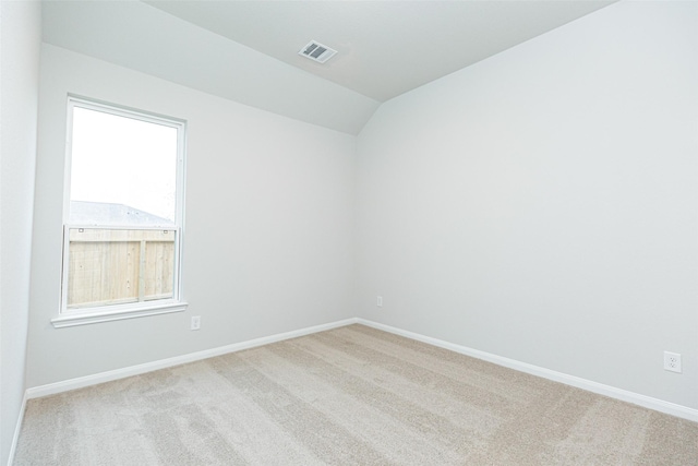 empty room featuring carpet floors, baseboards, visible vents, and lofted ceiling