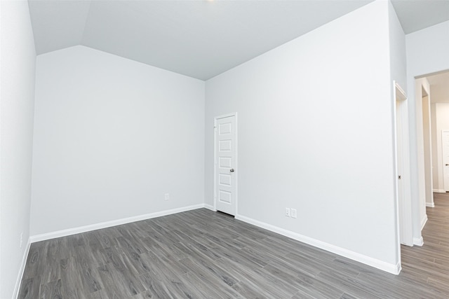 empty room featuring vaulted ceiling, baseboards, and wood finished floors