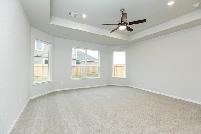 spare room featuring baseboards, visible vents, and a raised ceiling