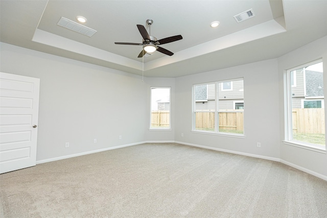 empty room featuring baseboards, visible vents, and a raised ceiling