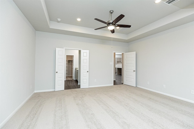 unfurnished bedroom featuring carpet, a raised ceiling, and baseboards