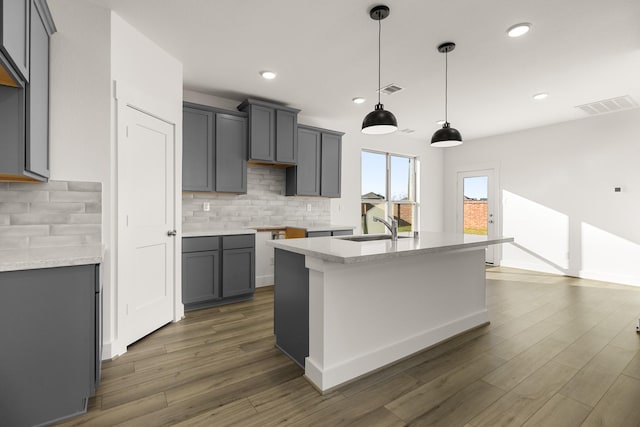 kitchen featuring sink, gray cabinets, hanging light fixtures, tasteful backsplash, and dark hardwood / wood-style flooring