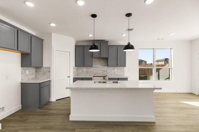 kitchen featuring sink, pendant lighting, gray cabinetry, hardwood / wood-style flooring, and a kitchen island with sink