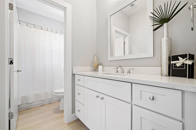 full bathroom featuring vanity, wood-type flooring, shower / bath combo with shower curtain, and toilet