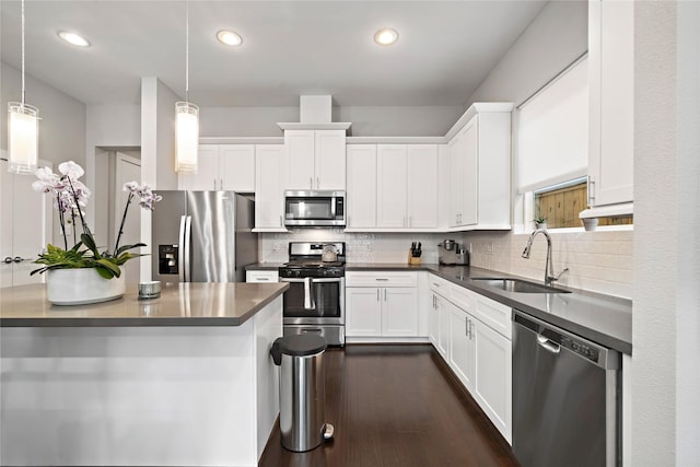 kitchen with pendant lighting, appliances with stainless steel finishes, sink, and white cabinets