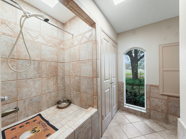 bathroom with a tile shower and tile walls