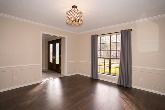 spare room with ornamental molding, plenty of natural light, dark wood-type flooring, and a notable chandelier