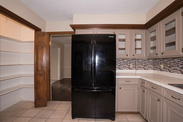 kitchen featuring black refrigerator, light tile patterned flooring, and decorative backsplash