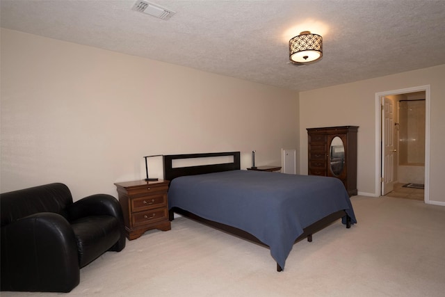 bedroom featuring light carpet, ensuite bath, and a textured ceiling