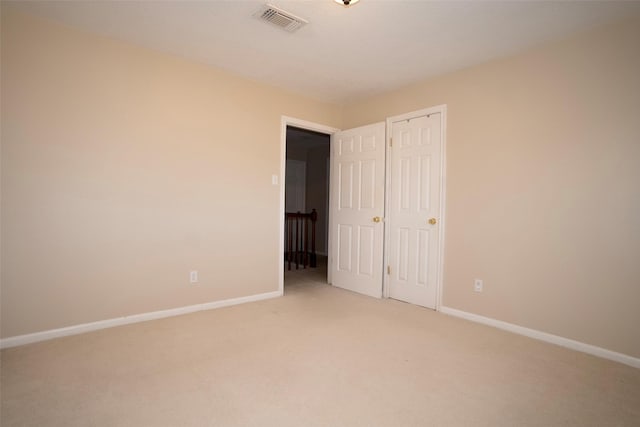 unfurnished bedroom with light colored carpet and a closet