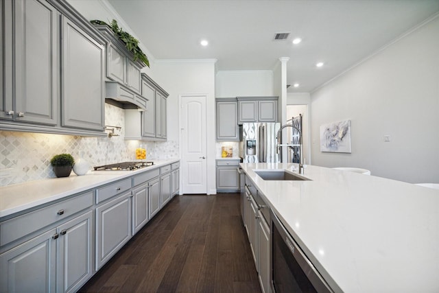 kitchen with tasteful backsplash, gray cabinetry, custom range hood, and appliances with stainless steel finishes