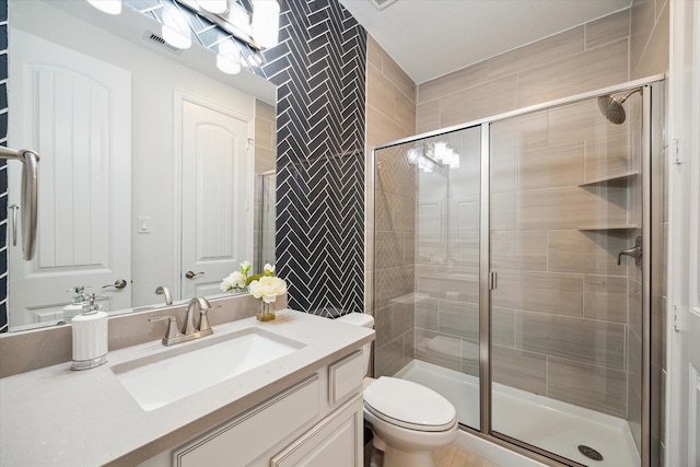 bathroom featuring vanity, a shower with shower door, and toilet