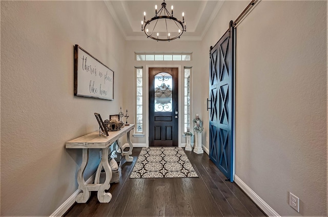 foyer entrance featuring dark hardwood / wood-style floors, ornamental molding, a barn door, and an inviting chandelier