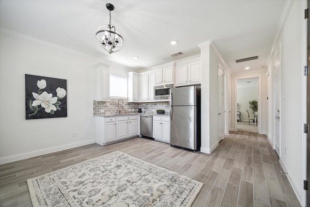 kitchen with sink, white cabinets, backsplash, stainless steel appliances, and crown molding