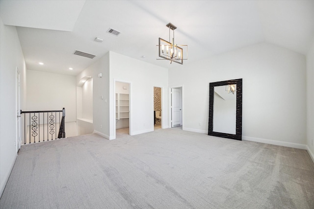 spare room with vaulted ceiling, light carpet, and a notable chandelier