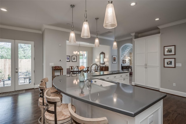 kitchen featuring white cabinetry, decorative light fixtures, sink, and a large island with sink