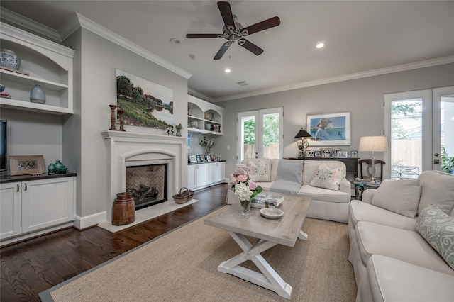 living room featuring crown molding, dark wood-type flooring, ceiling fan, built in shelves, and french doors