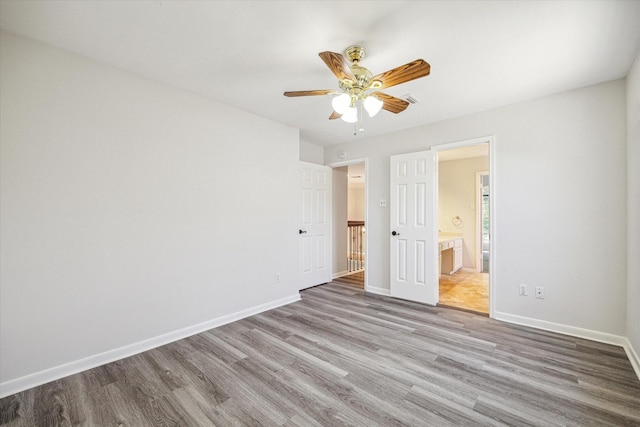 unfurnished bedroom with ensuite bathroom, ceiling fan, and light hardwood / wood-style floors