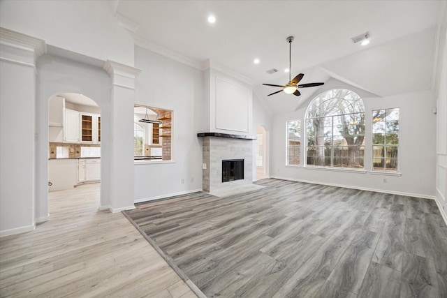 unfurnished living room with a tiled fireplace, vaulted ceiling, ceiling fan, and light hardwood / wood-style flooring