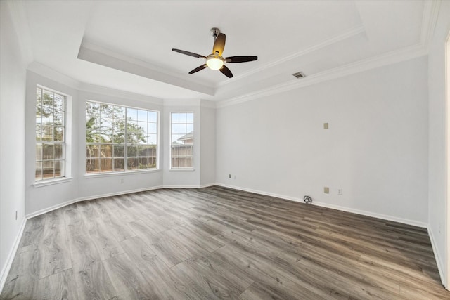 empty room featuring crown molding, a tray ceiling, ceiling fan, and hardwood / wood-style flooring