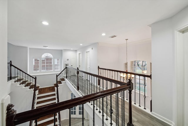 stairway featuring a notable chandelier, crown molding, and wood-type flooring