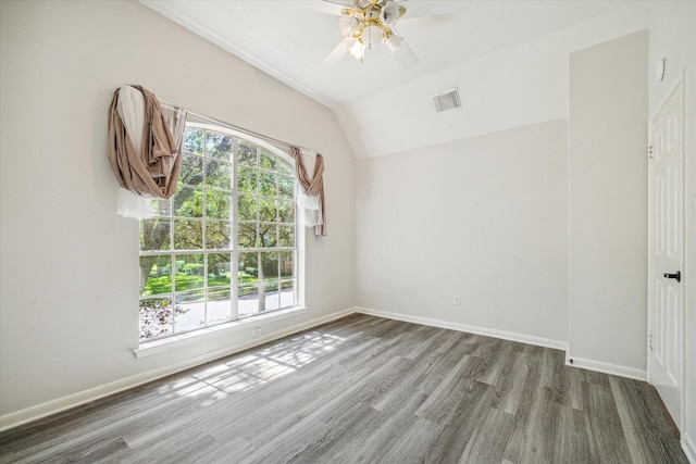 spare room featuring ceiling fan, vaulted ceiling, hardwood / wood-style floors, and a healthy amount of sunlight