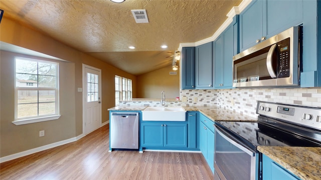 kitchen featuring appliances with stainless steel finishes, blue cabinets, sink, and kitchen peninsula