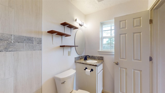 bathroom featuring vanity, a textured ceiling, and toilet