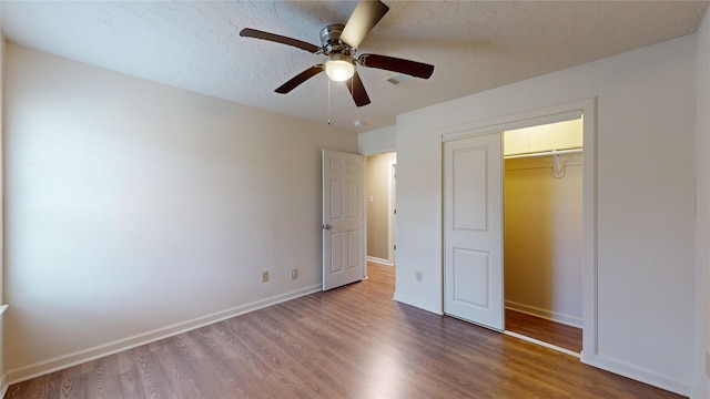 unfurnished bedroom featuring hardwood / wood-style floors, a textured ceiling, a closet, and ceiling fan