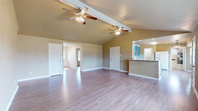 unfurnished living room featuring lofted ceiling with beams, ceiling fan with notable chandelier, light hardwood / wood-style floors, and a textured ceiling