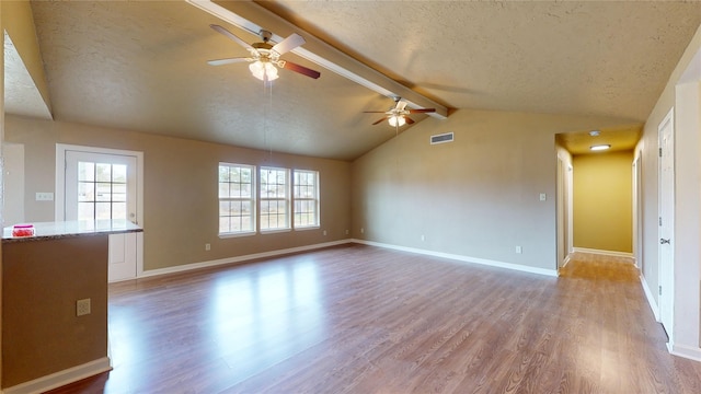 unfurnished living room featuring ceiling fan, light wood-type flooring, a textured ceiling, and vaulted ceiling with beams