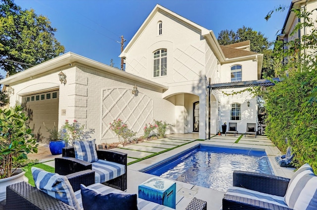 rear view of property featuring pool water feature, a garage, and a patio