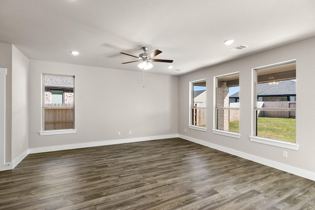 spare room featuring ceiling fan, a healthy amount of sunlight, and dark hardwood / wood-style floors