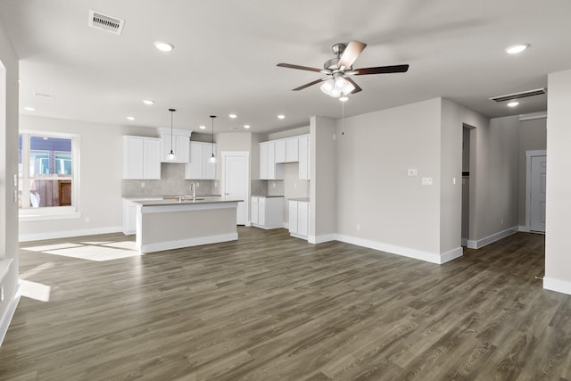 unfurnished living room featuring sink, dark hardwood / wood-style floors, and ceiling fan