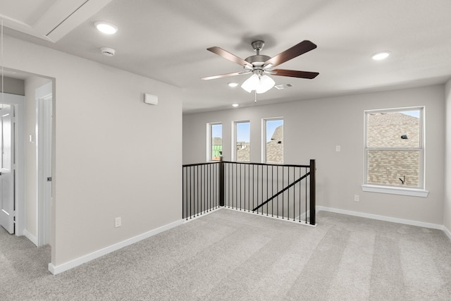 spare room with a wealth of natural light, light colored carpet, and ceiling fan