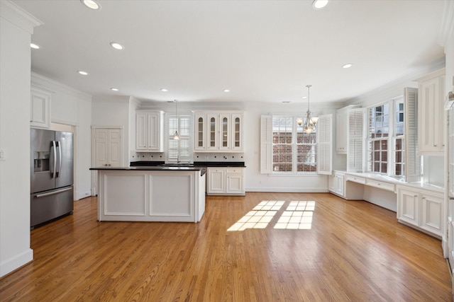 kitchen featuring a kitchen island, decorative light fixtures, white cabinetry, ornamental molding, and stainless steel fridge with ice dispenser