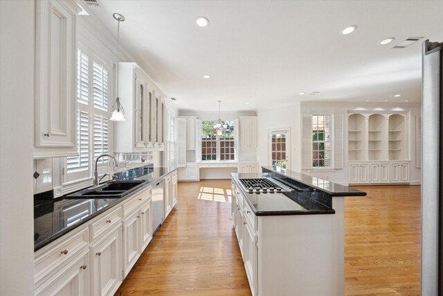 kitchen with sink, decorative light fixtures, appliances with stainless steel finishes, a kitchen island, and white cabinets