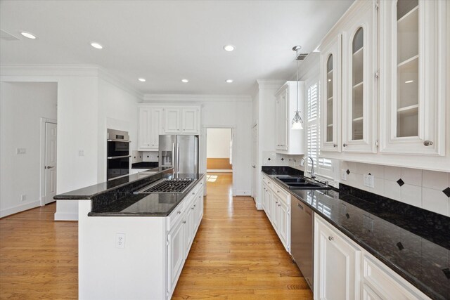 kitchen with white cabinetry, stainless steel appliances, decorative light fixtures, and sink