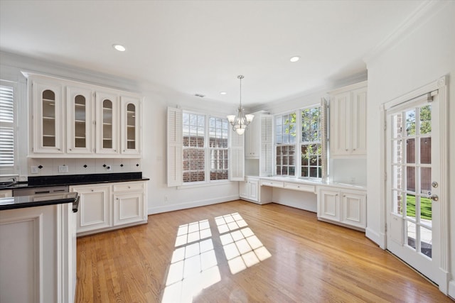 kitchen with pendant lighting, white cabinetry, ornamental molding, a healthy amount of sunlight, and light hardwood / wood-style flooring