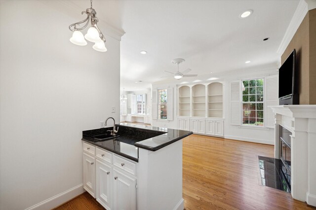 kitchen with white cabinetry, sink, kitchen peninsula, and built in shelves