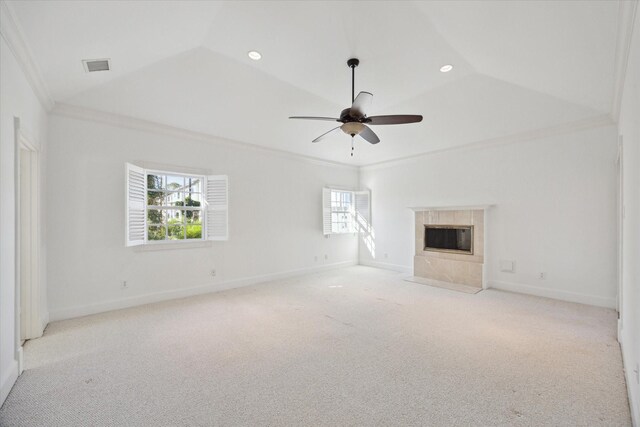 unfurnished living room featuring crown molding, a tile fireplace, ceiling fan, vaulted ceiling, and light colored carpet