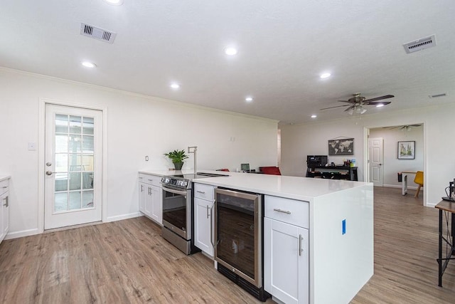 kitchen featuring crown molding, stainless steel range with electric stovetop, white cabinetry, wine cooler, and light wood-type flooring