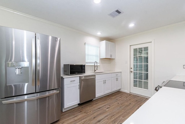 kitchen with white cabinetry, sink, light hardwood / wood-style floors, and appliances with stainless steel finishes