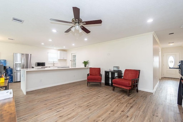 living area with ornamental molding, sink, ceiling fan, and light hardwood / wood-style floors