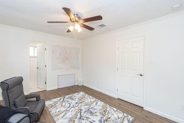 living area featuring hardwood / wood-style flooring, ornamental molding, and ceiling fan