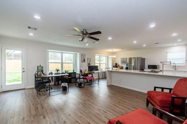 living room with hardwood / wood-style floors, ceiling fan with notable chandelier, ornamental molding, and sink