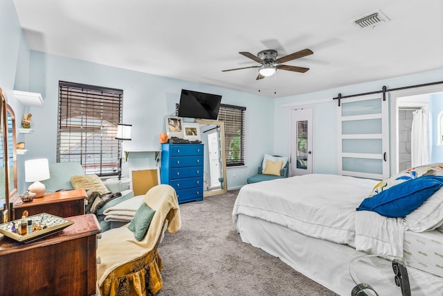 bedroom with multiple windows, ceiling fan, a barn door, and light carpet