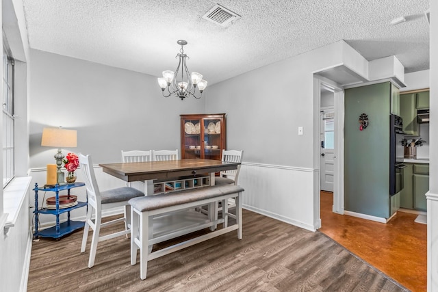 dining room with dark hardwood / wood-style floors, a notable chandelier, and a textured ceiling